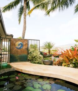 Side pedestrian gate Serene outdoor patio with lush plants and a small pond.