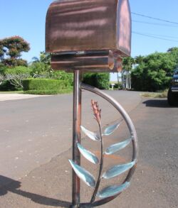 A metallic leaf sculpture with a square top mounted on a pole outdoors.