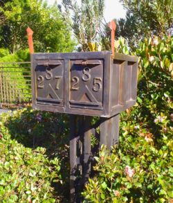 Rustic metal mailbox numbered 25 in a garden.