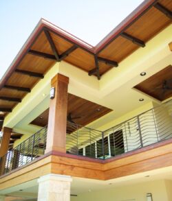 Modern house balcony with wooden and glass elements under a clear sky.