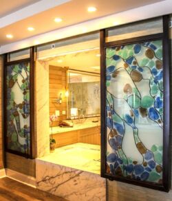 Elegant bathroom entrance with decorative stained glass panels featuring a bird design.