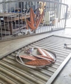 Large metallic leaf sculptures displayed on a conveyor belt.