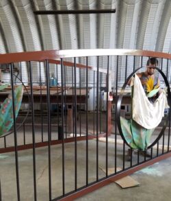 Man standing behind a metal gate in a rustic, semi-industrial space.