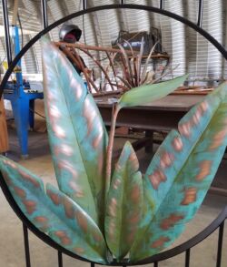 Decorative metal sculpture of succulent plants inside a circular frame.