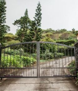 Wrought iron gate with stone pillars at a driveway entrance.