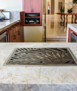 Modern kitchen island with built-in grill and marble countertop.