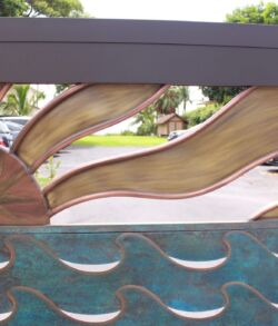 Decorative metal panel with sun and wave designs.