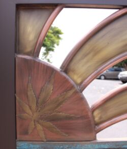 Close up of the Copper sun with the Hemp leaf in the center. Close-up of a wooden sculpture with curved beams and a sunburst design.