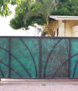 Framed full view. Decorative green metal fence panel with geometric patterns.