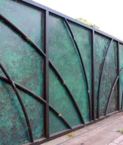 Decorative green metal fence with curved branch-like designs.