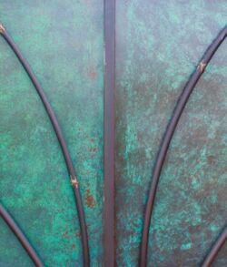 Close up view of gate center. Close-up of a greenish metal surface with curved decorative lines.