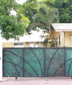 #17 Green metal gate with geometric design in front of a house.