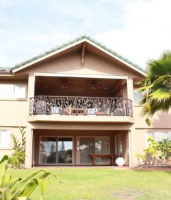 After, full view front of property Two-story house with balcony and garden under a clear sky.