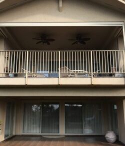 Before pictures Two-story balcony with white railings and ceiling fans.