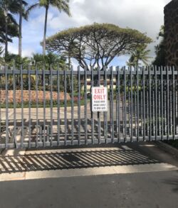 Closed gate with a warning sign in a tropical setting.