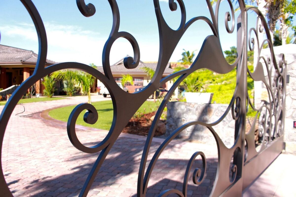 Decorative wrought iron gate with garden view behind.
