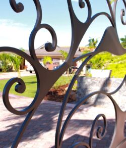 Decorative wrought iron gate with garden view behind.
