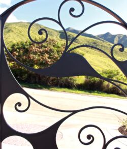Scenic mountain view framed by ornate wrought iron design.