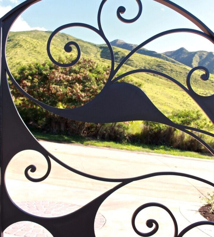 Scenic mountain view framed by ornate wrought iron design.