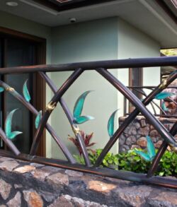 Side view of Panel. Decorative metal railing with bird designs on a stone wall.