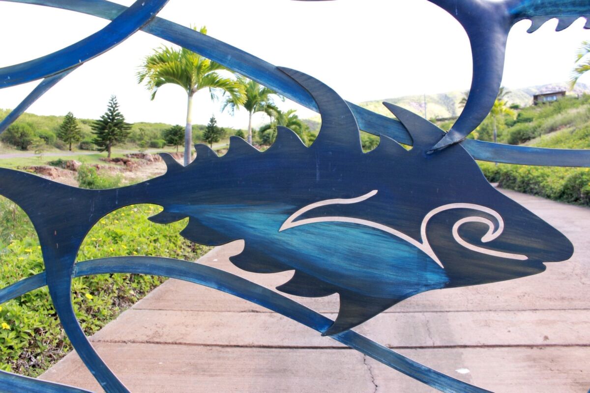 Decorative blue metal sculpture shaped like a stylized fish in an outdoor setting.