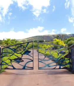 Decorative metal gate with mountain view and blue sky.