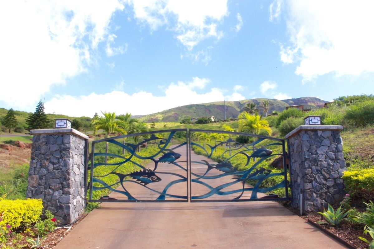Ornate metal gate with a scenic mountain backdrop under a blue sky.