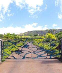 Ornate metal gate with a scenic mountain backdrop under a blue sky.