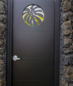 Black door with circular decorative window in stone wall.