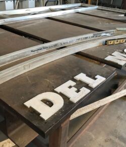 Wooden signs with white letters spelling 'DEL' laid out on a table.