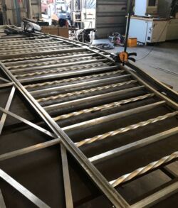 Large metal gate with intricate diagonal and vertical bars in a workshop.