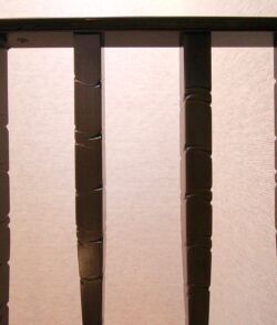 Close-up of a metal gate casting shadows on a white wall.