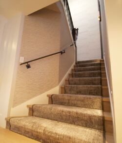 Carpeted staircase with beige walls and a handrail.