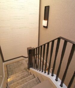 A narrow staircase with metal railings and beige carpeting.