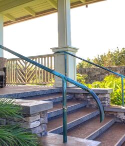 Outdoor stairs with metal handrails leading to a covered porch area.