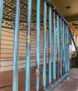 Rusty blue metal railing with peeling paint outside a house.