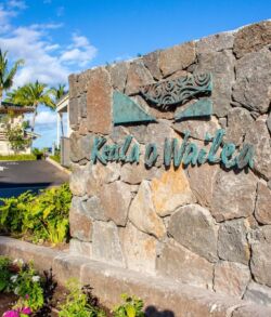 Stone sign reading 'Kahala at Waikiki' with tropical plants and blue sky.