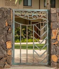 Decorative metal gate with geometric patterns and stone pillars.