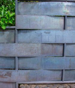 A close-up of a gray brick wall with some green foliage peeking over the top.