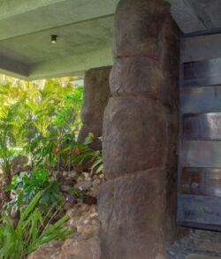 Ancient stone pillar with carvings near a modern building.