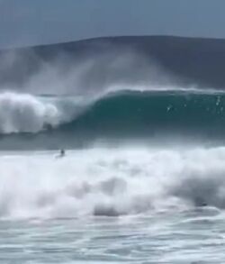 Surfer riding a large wave in the ocean.