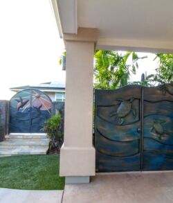 Modern driveway gate with artistic ocean wave design.