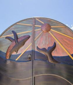 Sunset mural with a whale and a bird on a gate.