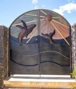 Artistic metal gate with dolphins and a rising sun.