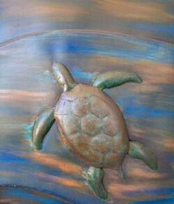 A carved wooden turtle with green flippers on a polished surface.
