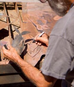 A person crafting metal art on a workbench.
