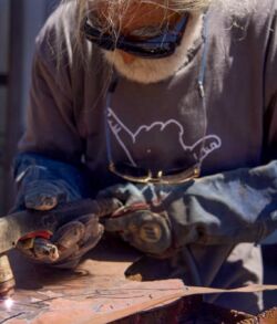 Bearded artisan welding decorative steel panel
