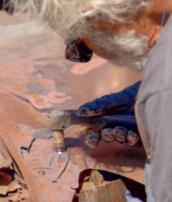 A person painting detailed designs on pottery.