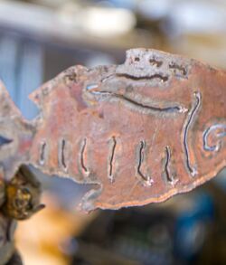 Close-up of a rusted fish-shaped metal artifact with engraved details.