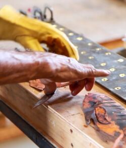 Hands painting white dots on fabric using a wooden block.
